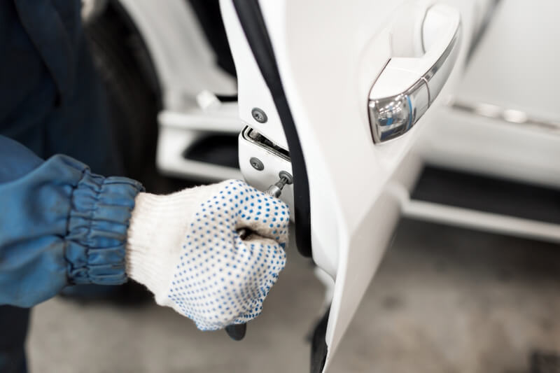 Gloved hand working the latch of a white car door