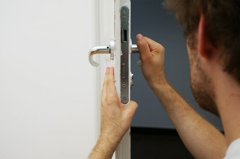Locksmith fitting a mortise lock into a commercial door