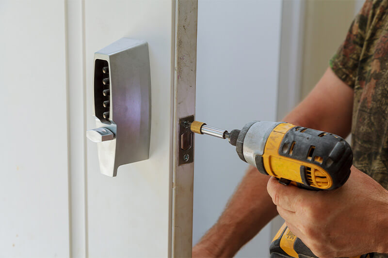 Keypad deadbolt being installed on a house door with a drill
